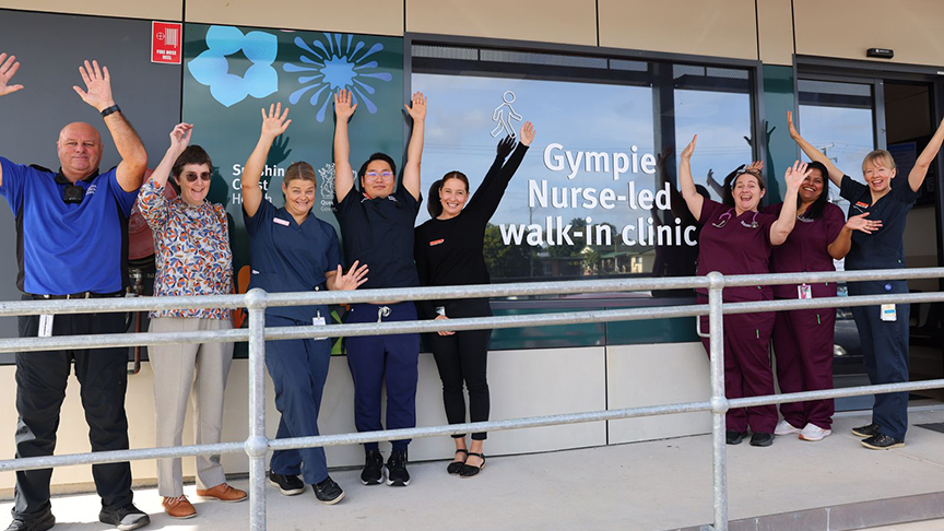 A group of people with their arms in the air standing outside Gympie Nurse-led Walk-in Clinic