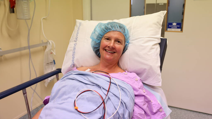 A patient smiling on a hospital bed as they prepare to go to surgery