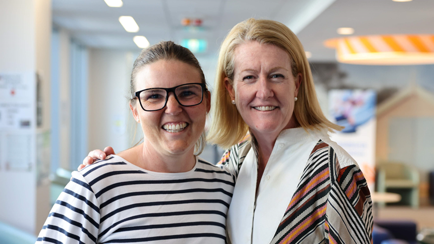 Headshot of two smiling women in a hospital waiting room.