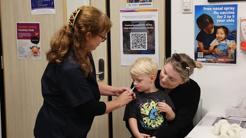 A Nurse preparing to give a vaccination to a child sat with their mother