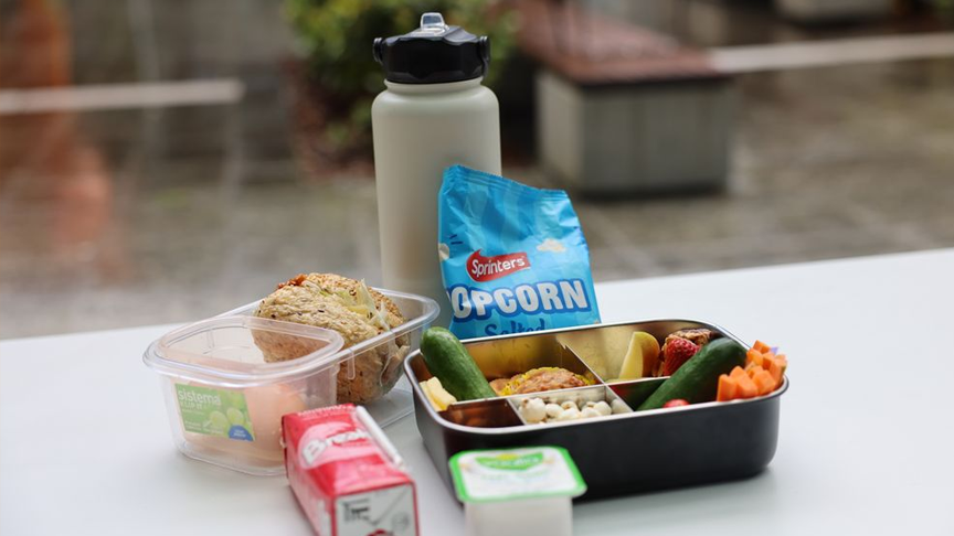 A lunchbox, food items and a water bottle on a table